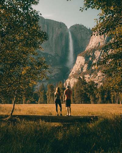 walking couple standing on tree trunk looking at field and forest tree